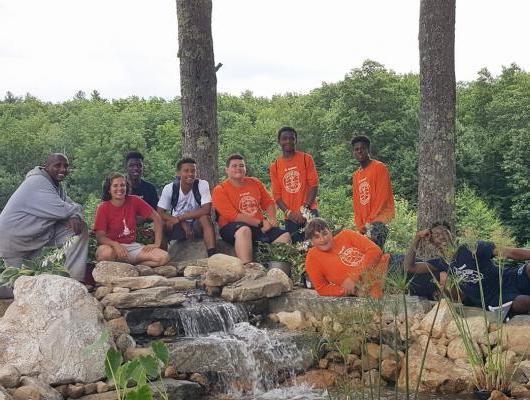 岩浆设计集团在罗恩伯顿训练村与一群孩子坐在瀑布